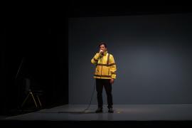 Un comédien debout dans une veste jaune fluo