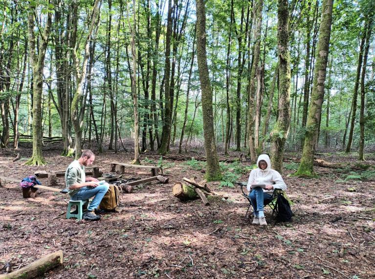 Des personnes dessinent sous des arbres