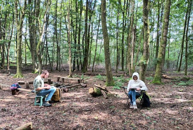 Des personnes dessinent sous des arbres